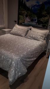 a bed with a gray and white comforter and pillows at le scuderie di s.Bakhita in Schio