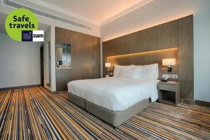 a hotel room with a large bed and a sign that says safe travels at Naumi Hotel Dubai in Dubai