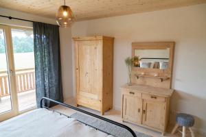 een slaapkamer met een bed, een houten kast en een raam bij Heimat-Raum in Bayersoien