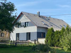 uma casa branca com um telhado preto e uma cerca em Čtyři pokoje em Tachov