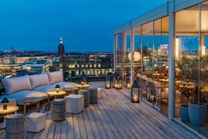 eine Dachterrasse mit einem Sofa und Tischen auf einem Gebäude in der Unterkunft Hobo Hotel Stockholm in Stockholm