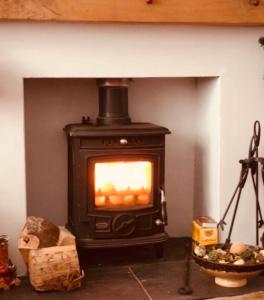 a stove in a room with a fireplace at PondeROSEa Cottage Free Gated Parking M1 & City location, wood stove in Lisburn