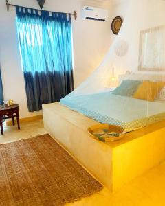 a bedroom with a large bed with a blue curtain at FURAHA VILLA 3 in Chanjani