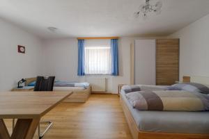 1 dormitorio con 2 camas y mesa de madera en Haus Schimpfössel, en Flirsch