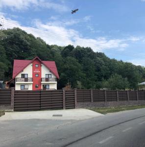 a house behind a fence with a plane flying overhead at Casa Elysium in Vălenii de Munte