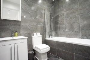 a bathroom with a toilet and a sink and a tub at Premium Apartments Thatcham Broadway in Thatcham