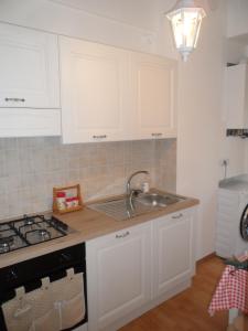 een keuken met witte kasten, een wastafel en een fornuis bij La Vie En Rose in Rapallo