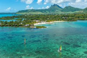 two sailboats in the water next to a small island at Four Seasons Resort Mauritius at Anahita in Beau Champ