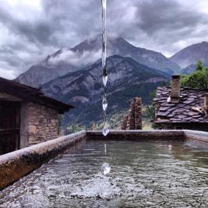 a pool of water with mountains in the background at Hotel Chez Toi in Oulx