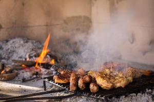 a grill with meat on it with smoke and flames at Villa Stipanovi Dvori in Vodenjak