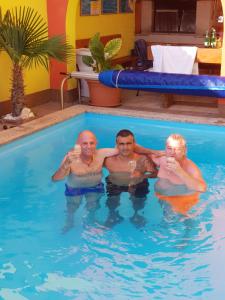 three men in a swimming pool drinking wine at Apartments Maslina in Crikvenica