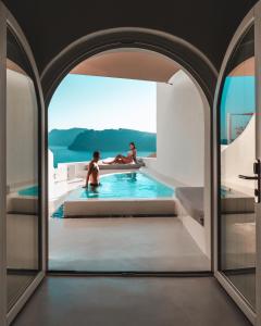 a man and a woman sitting in a tub in a swimming pool at Aspaki by Art Maisons in Oia