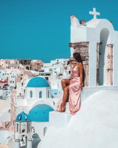 a woman sitting on top of a white building at Aspaki by Art Maisons in Oia