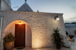 a white brick building with a door and plants at Trullo Pentimelle in Martina Franca