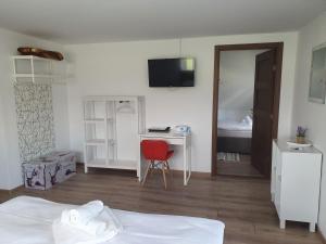 a bedroom with a bed and a desk with a red chair at Casa Saga in Gura Humorului