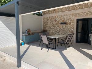 a patio with a table and chairs and a stone wall at Villa Kamena in Vitina