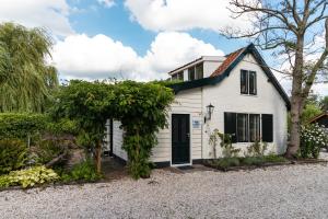 a white house with a black door and trees at Gastenverblijf KortVertoef in Kortenhoef