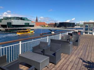 a deck with chairs and a boat on a river at Hotel CPH Living in Copenhagen