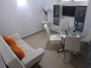 sala de estar con mesa de cristal y sillas blancas en Apartamentos Marques De La Merced, en Málaga