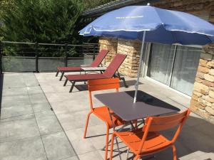 einen Tisch und Stühle mit Sonnenschirm auf einer Terrasse in der Unterkunft La Villa du Rhône in Miribel