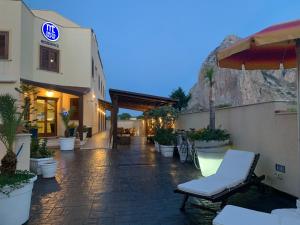 a building with a patio with chairs and an umbrella at Residence Hotel Marino Tourist in San Vito lo Capo