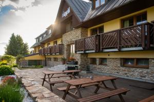 two wooden picnic tables in front of a building at Apartmány Engadin in Boží Dar