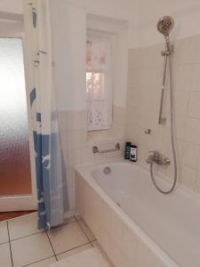a bathroom with a white tub and a shower at Pension Becker Luckenwalde in Luckenwalde