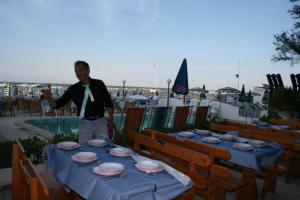 Un uomo in piedi accanto a un tavolo con dei piatti sopra. di Hotel Internazionale a San Mauro a Mare