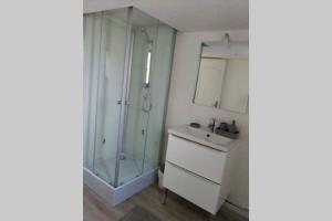 uma casa de banho com uma cabina de duche em vidro e um lavatório. em charmante maison normande luneray em Luneray