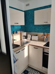 a kitchen with white cabinets and blue tiles at GuestHouse Bord de Seine in La Frette-sur-Seine