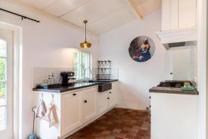a kitchen with white cabinets and black counter tops at Gastenverblijf KortVertoef in Kortenhoef +16 photos