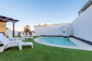 a backyard with a swimming pool and chairs and grass at Villa Annalisa in Corralejo