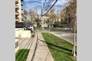 eine Stadtstraße mit Bürgersteig und Baum in der Unterkunft Ideal departamento en el corazón de Los Dominicos in Santiago