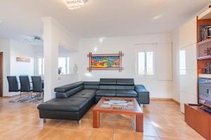 sala de estar con sofá de cuero negro y mesa en Villa Annalisa, en Corralejo
