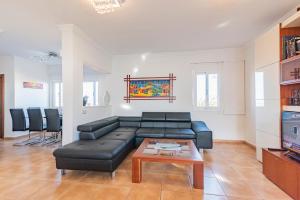 a living room with a black leather couch and a table at Villa Annalisa in Corralejo