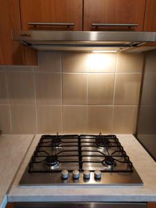a stove top in a kitchen with a hood at Dzīvoklis in Ventspils