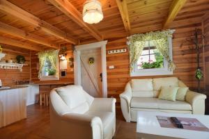 a living room with two white couches and a kitchen at Wilkowa Chata in Wilków