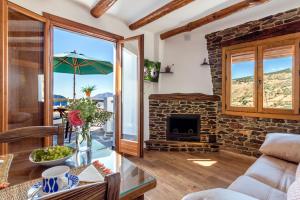 a living room with a stone fireplace and a couch at Apartamentos Entre Senderos in Capileira