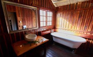 a wooden bathroom with a tub and a sink at Rain Farm Game Lodge in uMhlali