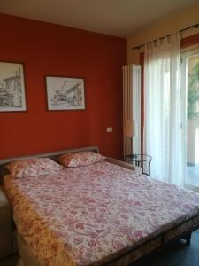 a bedroom with a bed with orange walls and a window at Cascina nel Bosco in Cannobio