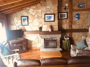 a living room with a stone fireplace and a couch at Artesano II in Navarredonda de Gredos