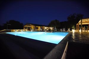 uma grande piscina à noite com cadeiras à volta em Agriturismo La Noce em Bassano Romano