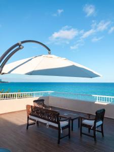 a patio with two benches and an umbrella at Hotel Llorca in Platja de l’Almadrava