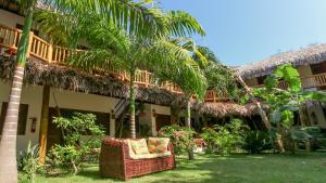 a resort with a chair and palm trees in the yard at Residence Bons Ventos Jeri in Jericoacoara