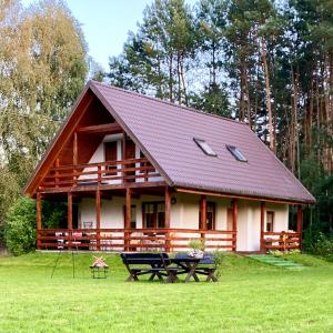 una cabaña de madera con una mesa de picnic delante de ella en Domek nad Wkrą en Popielżyn Górny