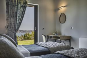 dwa łóżka w pokoju z dużym oknem w obiekcie Alekos Beach Houses-Elia Villas w Lixoúrion