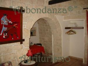 Habitación con una pared de piedra y una pintura roja. en Abbondanza® Agriturismo, en Alberobello