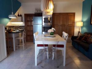 eine Küche und ein Wohnzimmer mit einem weißen Tisch und Stühlen in der Unterkunft Casa Paola e Guido in Posada