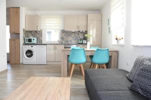 a kitchen and living room with a table and blue chairs at Menta Lak in Balatongyörök