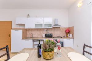 kuchnia z białymi szafkami i drewnianym stołem w obiekcie Apartment Markovic w Trogirze